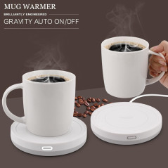 A white mug filled with latte art sits on a sleek white heating coaster, with steam rising from the cup.